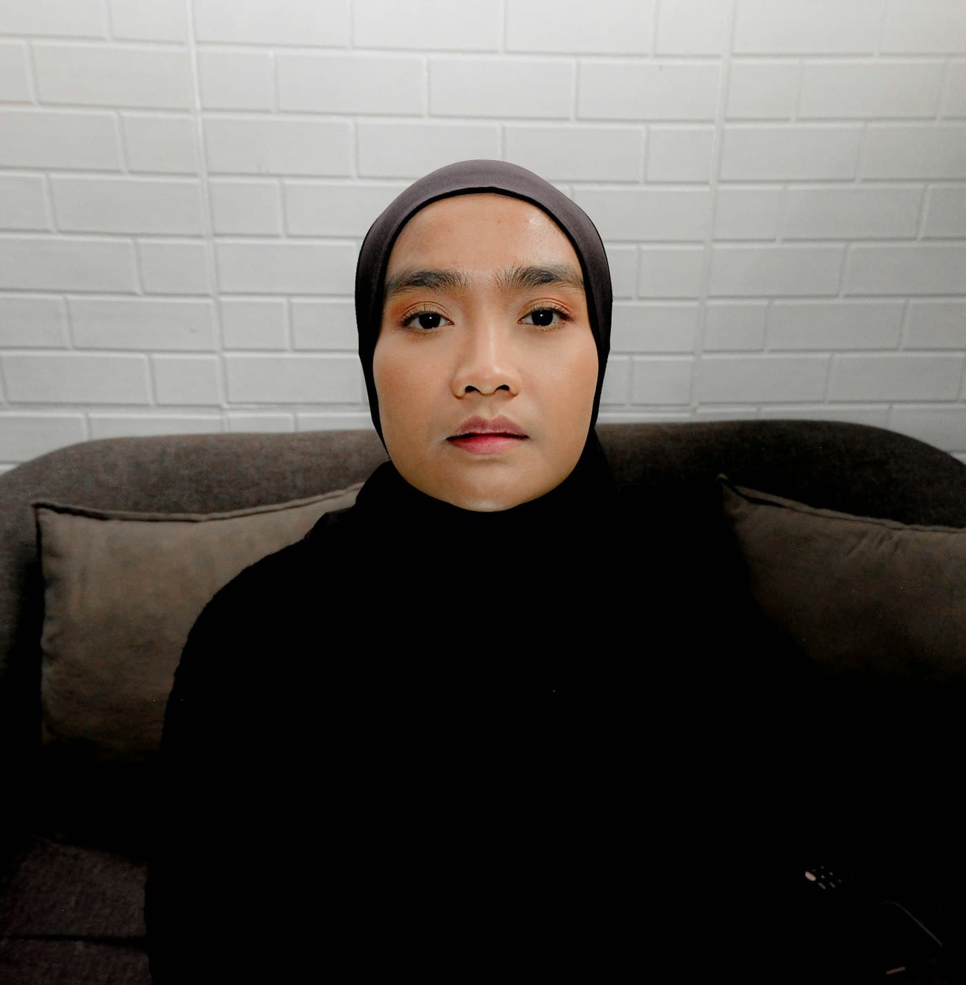 Perempuan berhijab gelap berfoto menghadap kamera